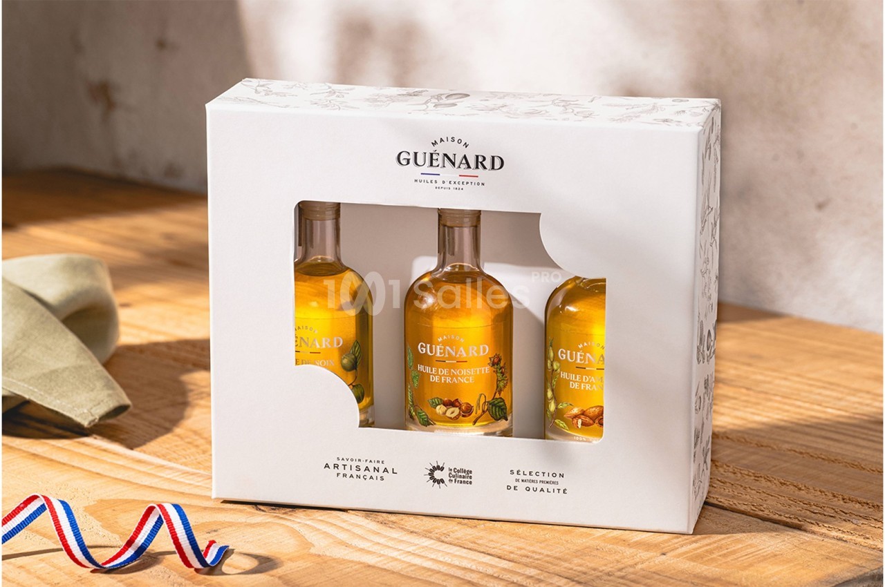 Coffret de trois bouteilles d'huiles artisanales françaises sur une table en bois, éclairé par une lumière naturelle.