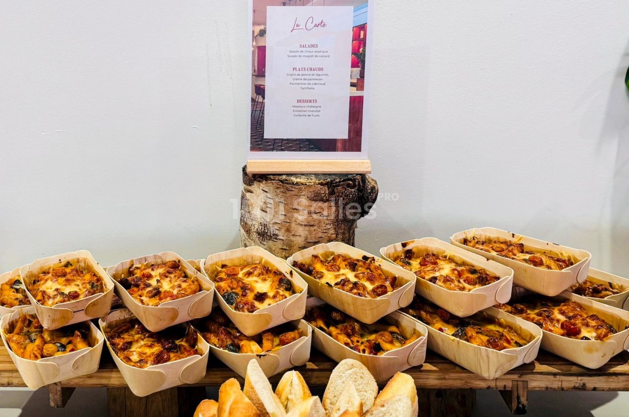 Quiches individuelles disposées sur une table en bois, accompagnées de pains tranchés, avec un menu en arrière-plan.