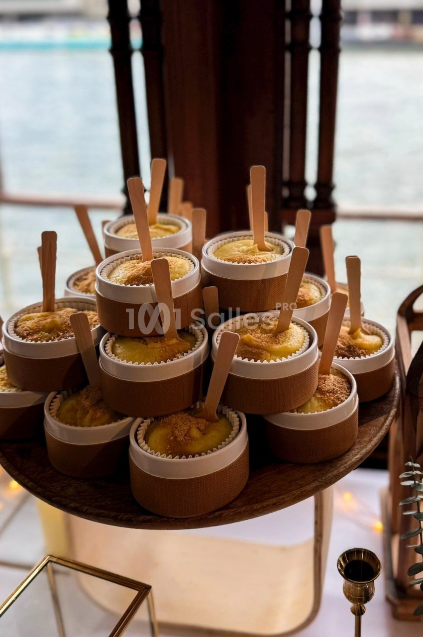 Desserts individuels présentés dans des pots en bois avec des cuillères, disposés sur un plateau près d'une fenêtre.