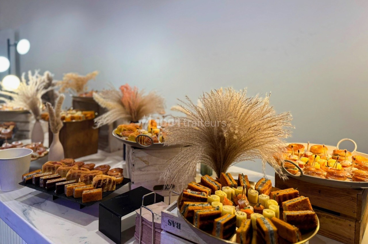 Buffet de pâtisseries variées disposées sur des plateaux en bois, décoré avec des bouquets d'herbes séchées.