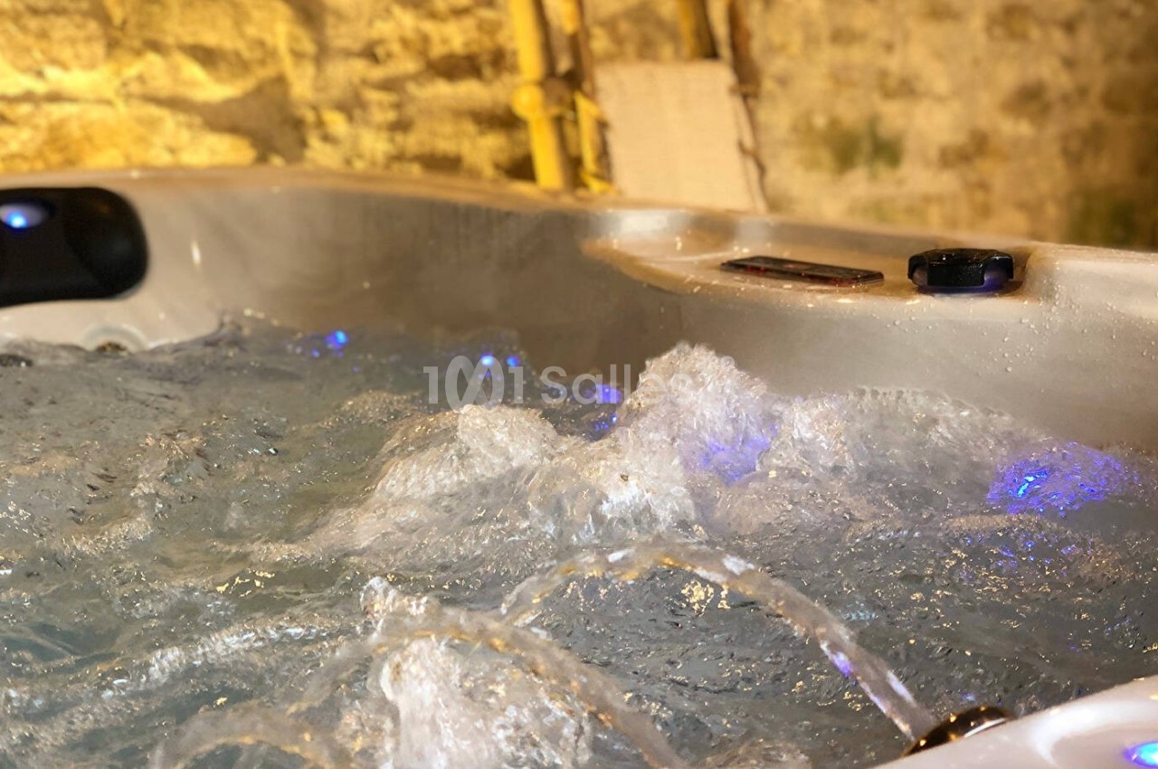 Eau bouillonnante d'un jacuzzi en fonctionnement dans un espace intérieur aux murs en pierre.