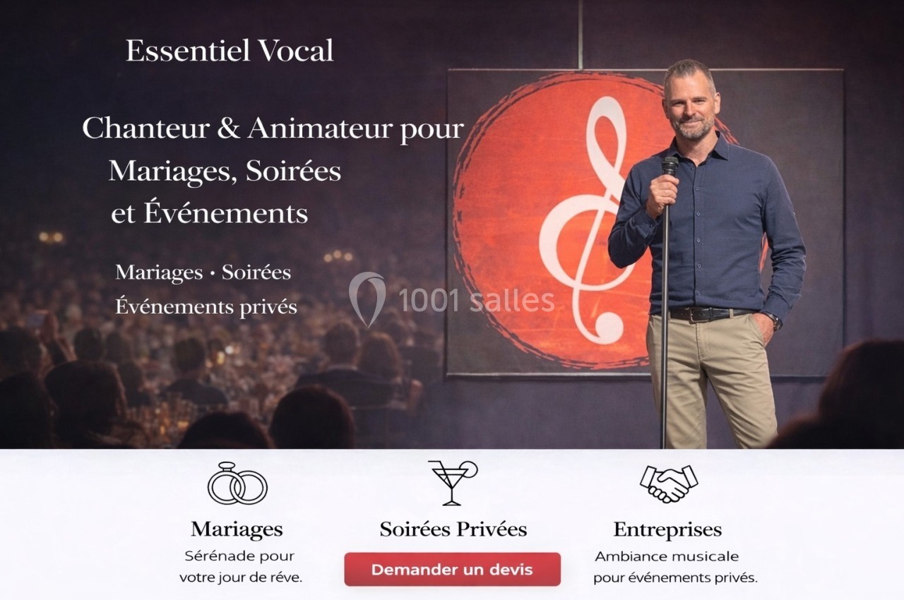 Un homme souriant tient un micro sur scène devant un public, avec un grand logo de clé de sol en arrière-plan.