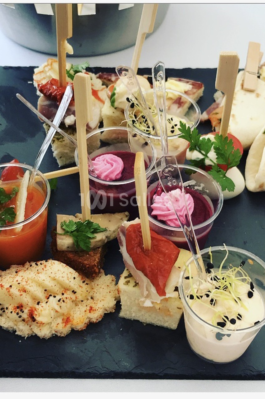 Plateau de bouchées apéritives variées comprenant verrines, toasts, wraps et décorations culinaires.