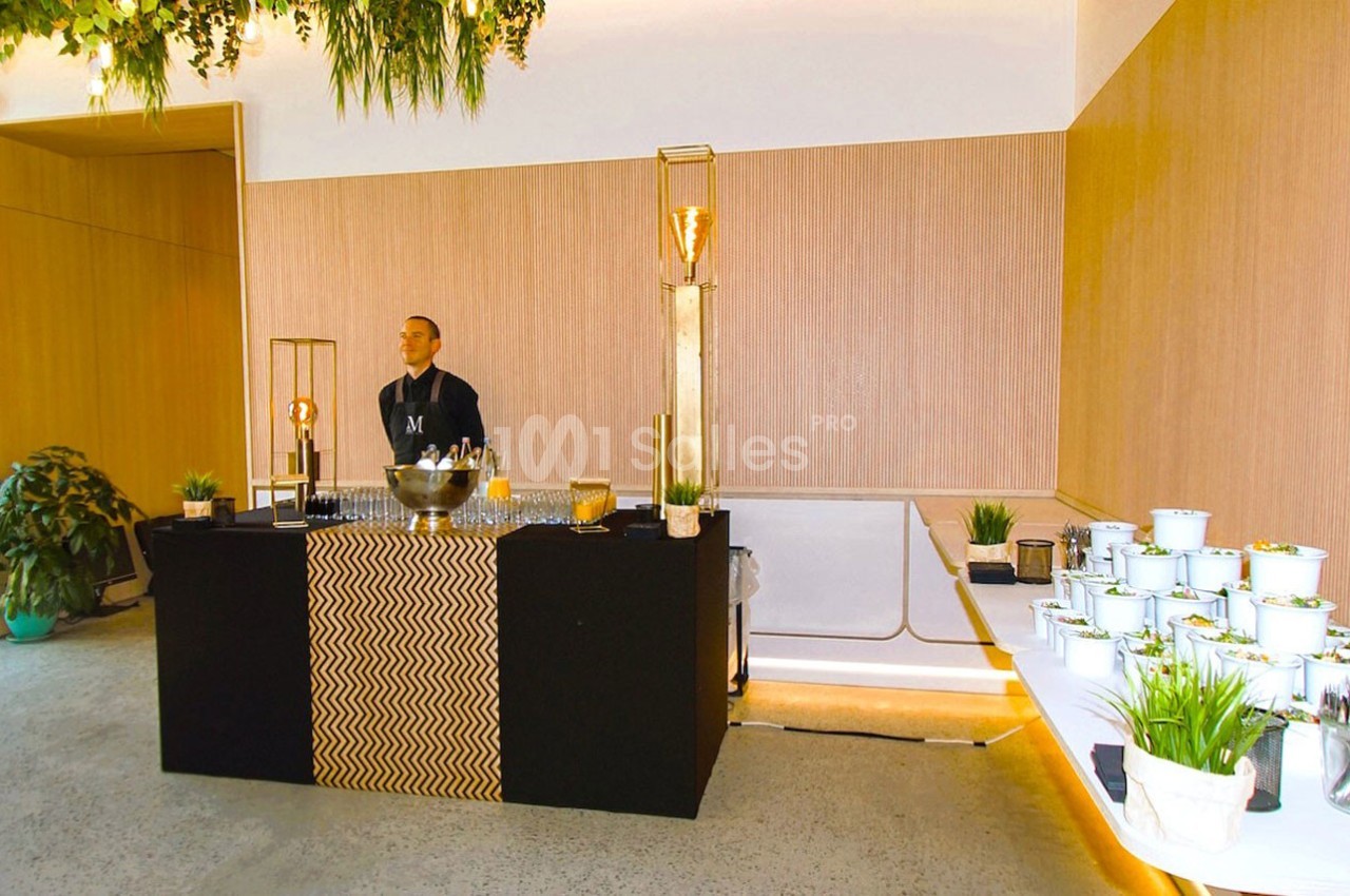 Un buffet élégant avec un serveur derrière un comptoir noir, entouré de plantes et de décorations modernes.
