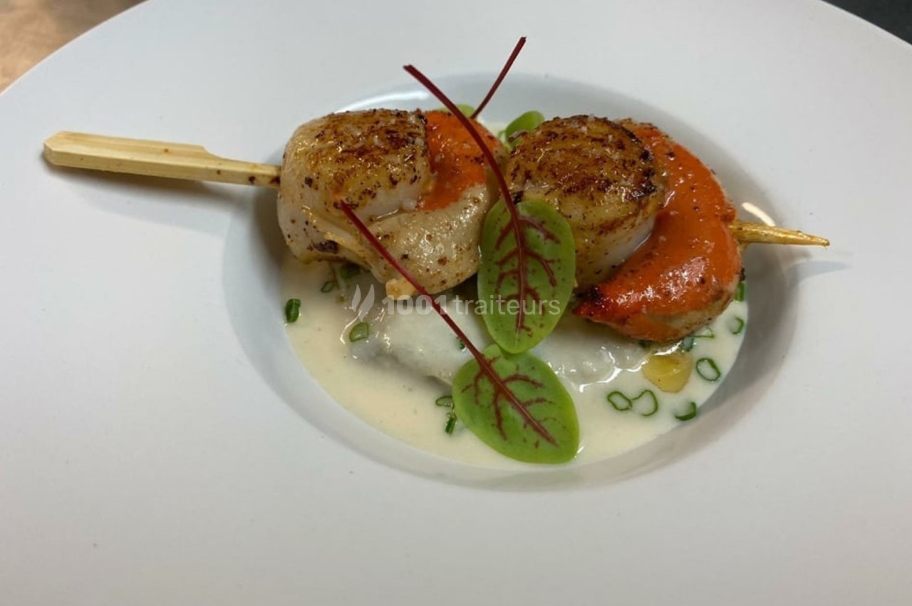 Brochette de noix de Saint-Jacques grillées, servie sur une sauce crémeuse avec garniture de jeunes pousses.