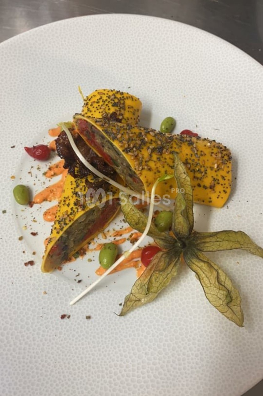 Rouleaux garnis présentés sur une assiette blanche, décorés de graines, sauce colorée, baies et physalis.