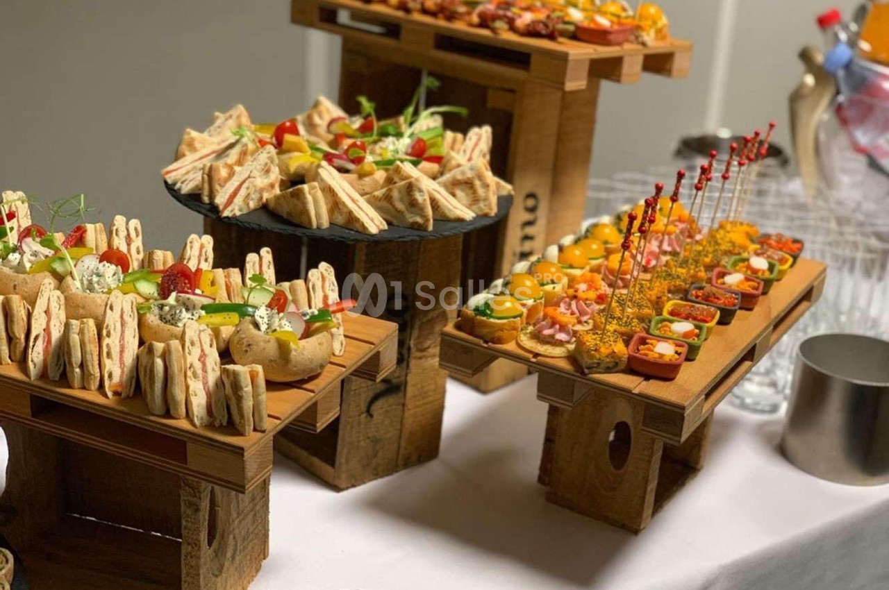 Plateau de buffet avec assortiments de sandwichs, brochettes, verrines et amuse-bouches colorés sur présentoirs en bois.
