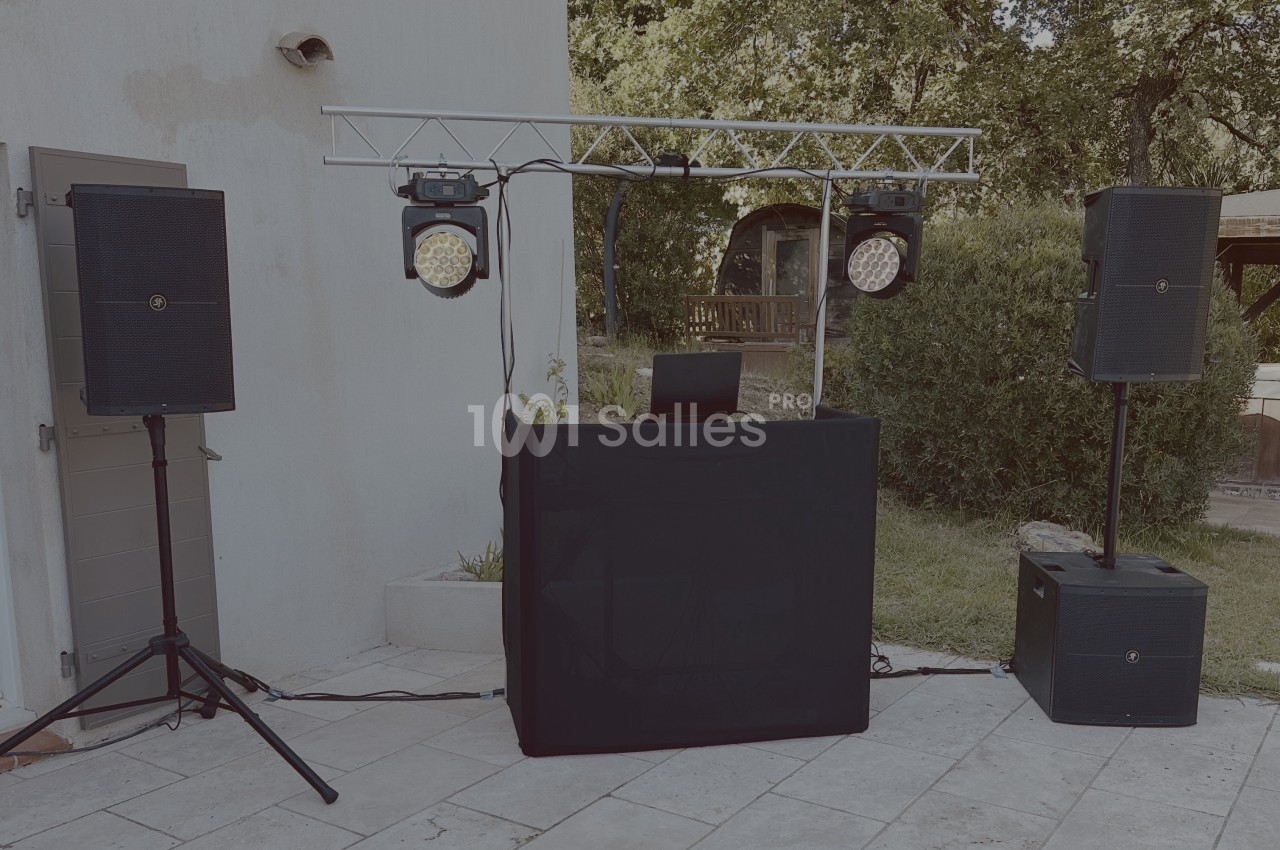 Installation de matériel de sonorisation et d'éclairage en extérieur, avec une table de mixage et des enceintes.