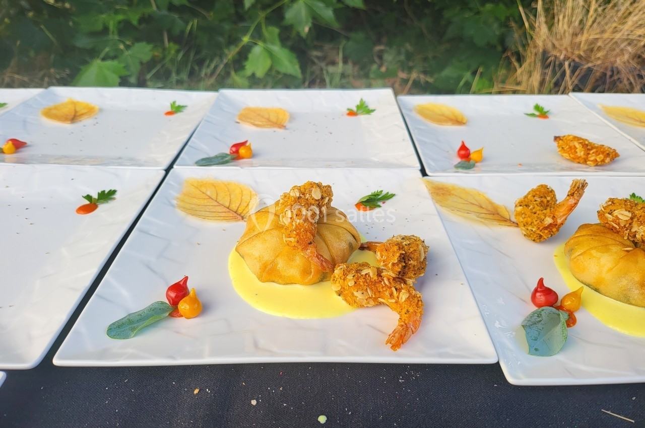 Assiettes dressées avec des croustillants de crevettes, sauce jaune, légumes décoratifs et feuilles en décoration.