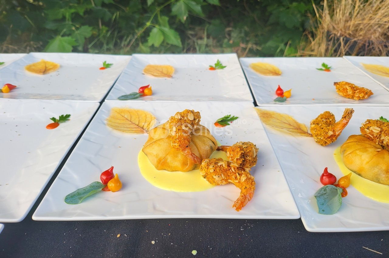 Assiettes dressées avec des croustillants de crevettes, sauce jaune, légumes décoratifs et feuilles en décoration.