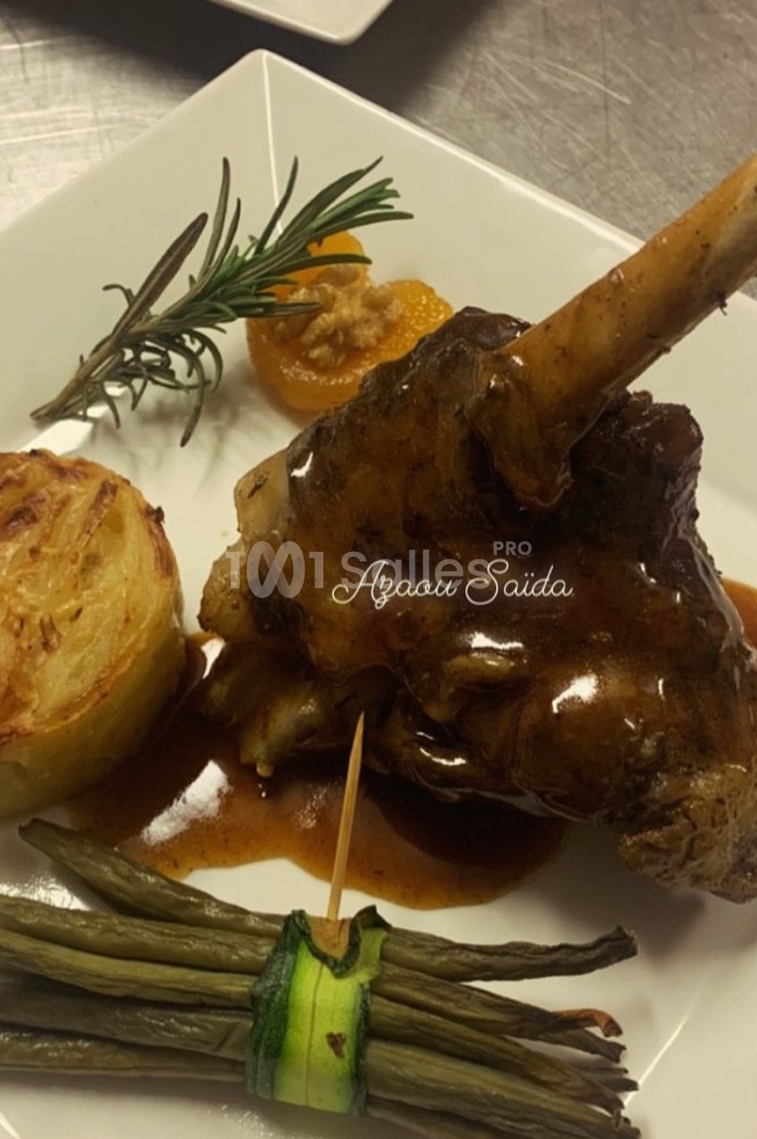 Plat de jarret d'agneau en sauce, accompagné de gratin dauphinois, haricots verts et décoration d'herbes.