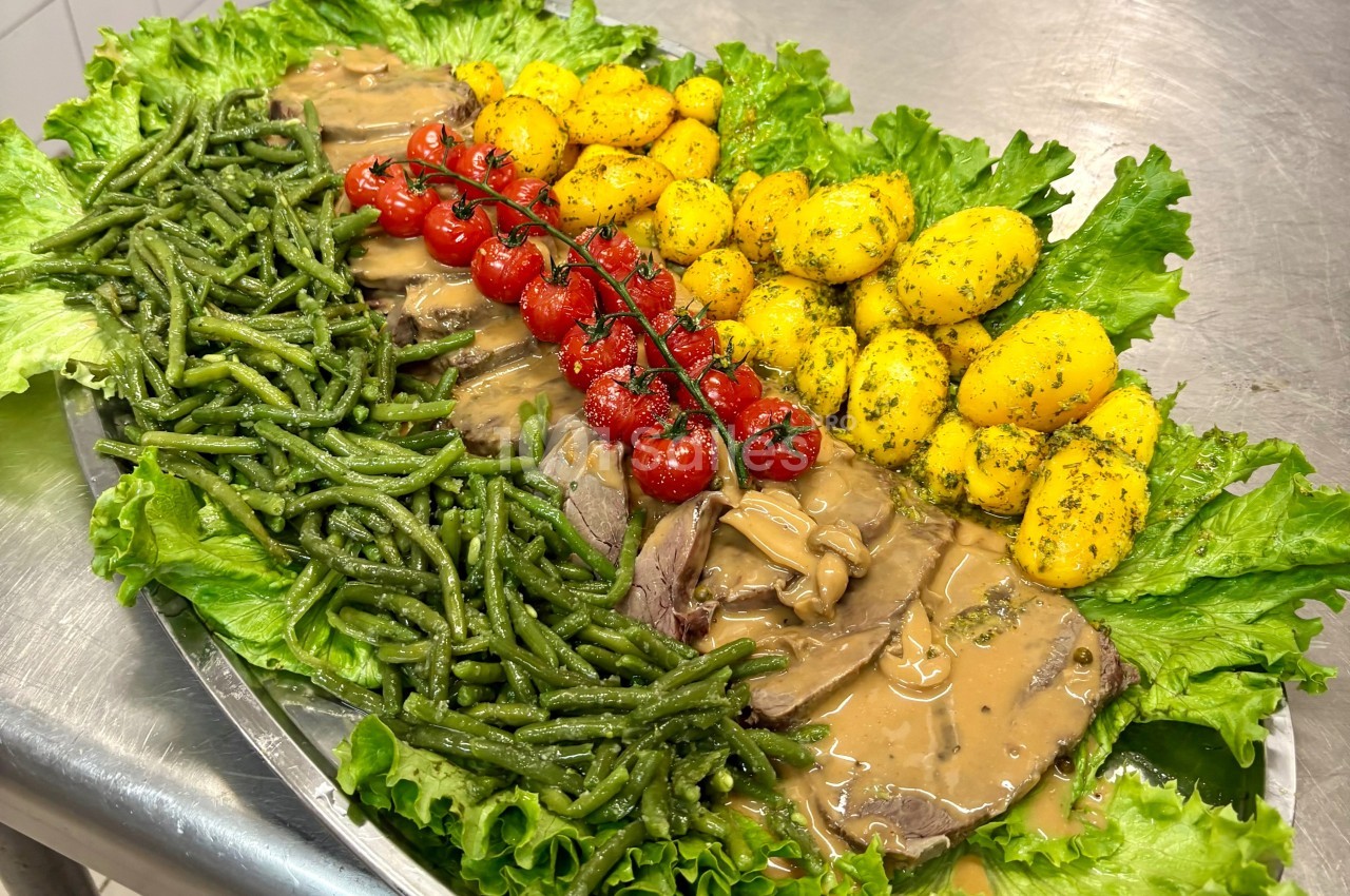 Plateau garni de rôti en sauce, haricots verts, pommes de terre persillées, tomates cerises et feuilles de salade.