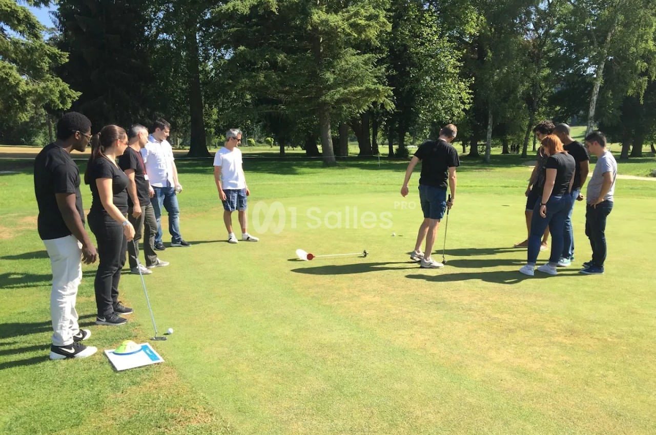 Un groupe de personnes observe un joueur de golf sur un terrain entouré d'arbres.