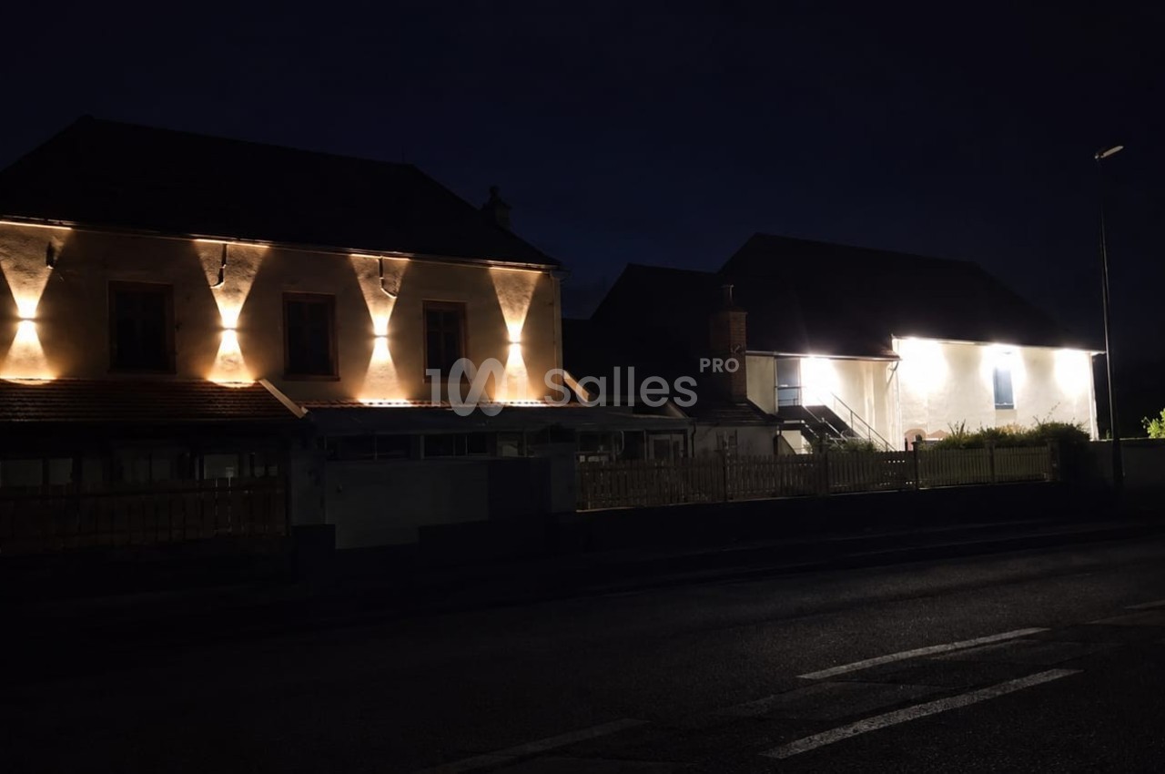 Façades de maisons éclairées par des lumières chaudes dans une rue sombre pendant la nuit.