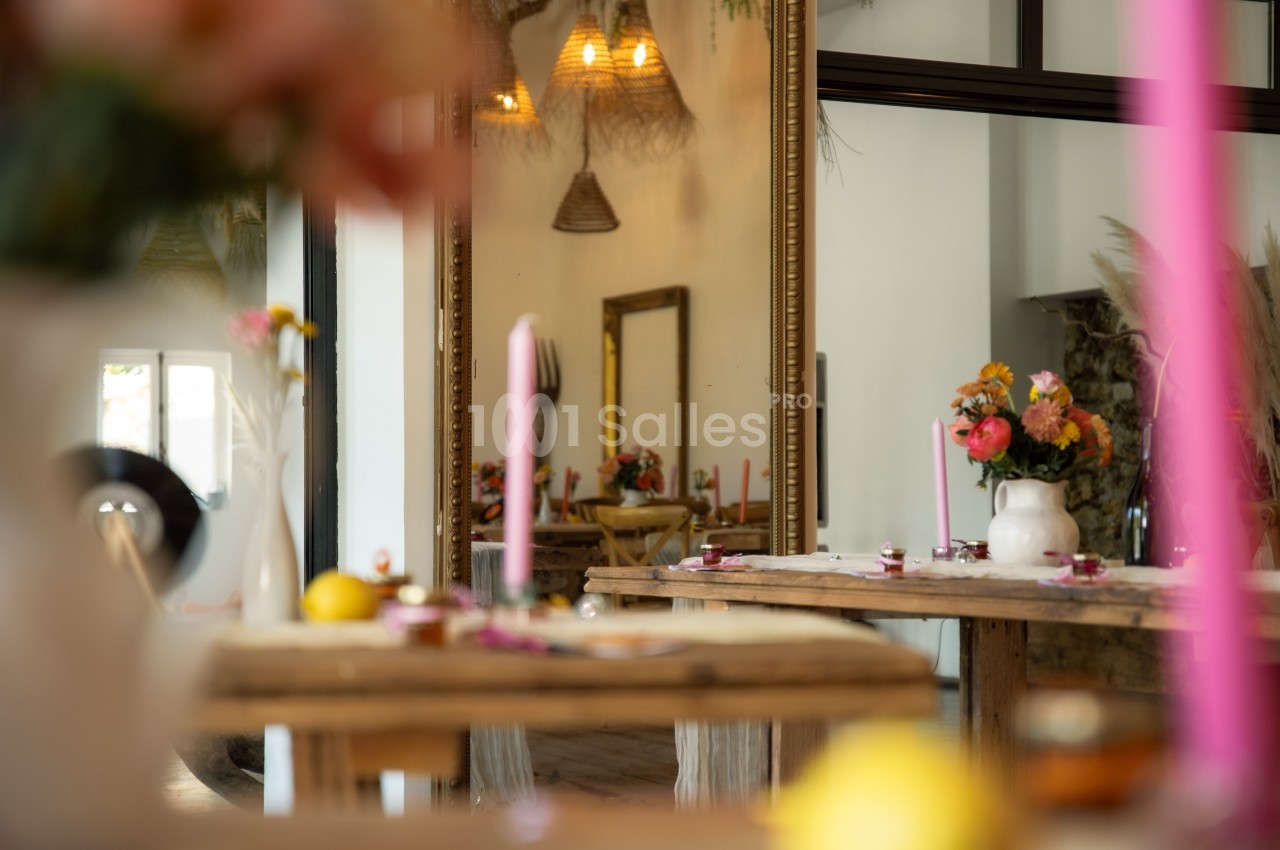 Salle décorée avec des fleurs colorées, des bougies roses et un grand miroir reflétant l'ensemble.