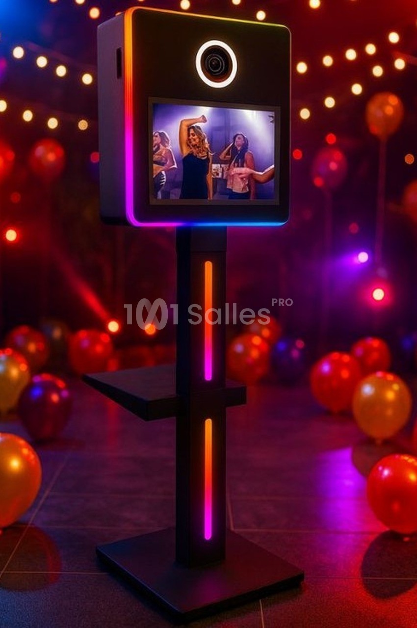 Borne photo lumineuse avec écran affichant des personnes dansant, entourée de ballons et d'éclairages festifs.