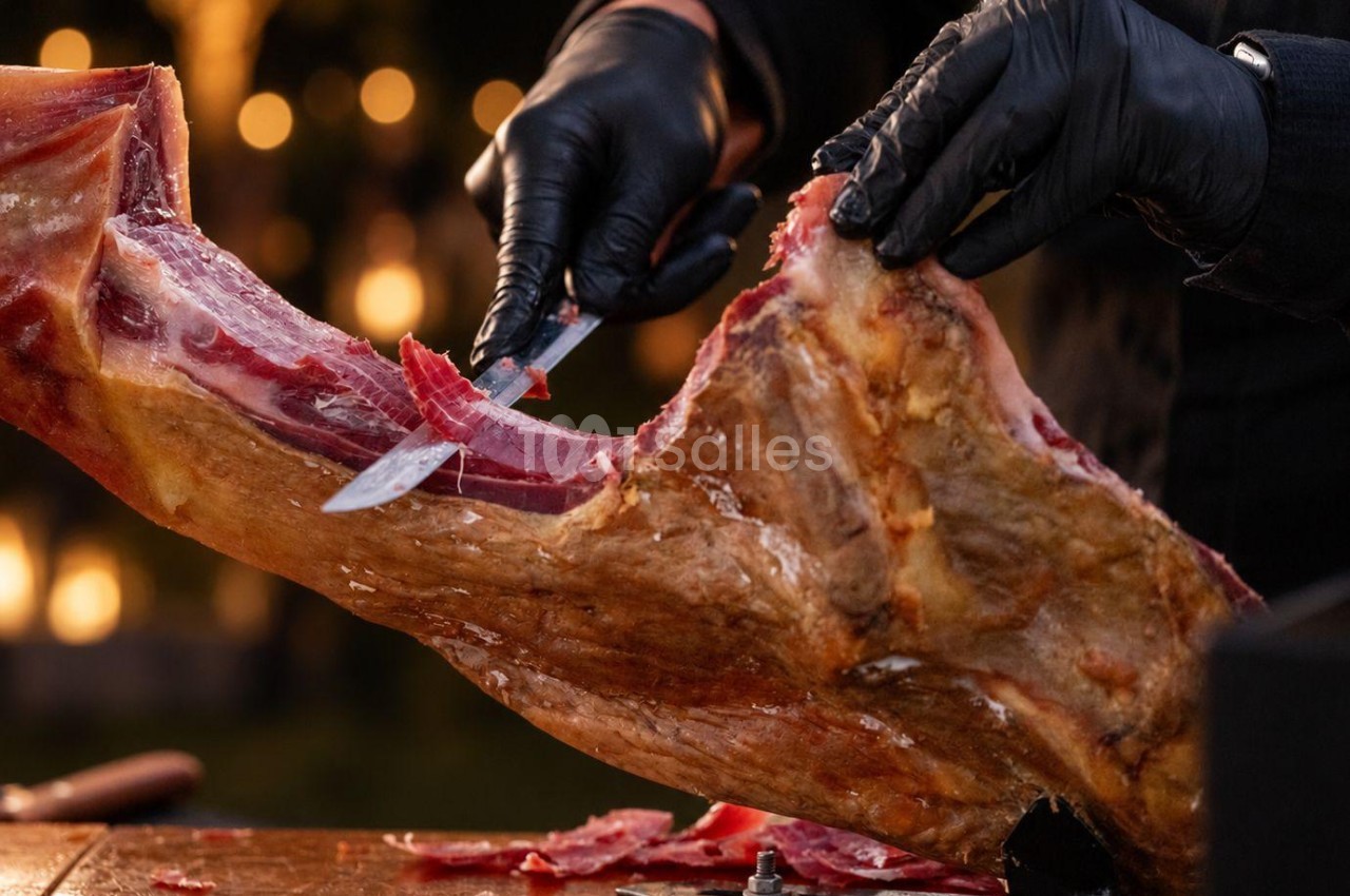 Mains gantées découpant au couteau une viande rôtie sur fond d'éclairage chaleureux.