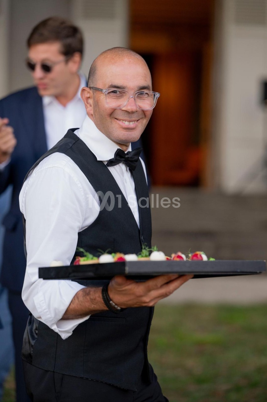 Serveur en tenue formelle tenant un plateau de canapés lors d'un événement.
