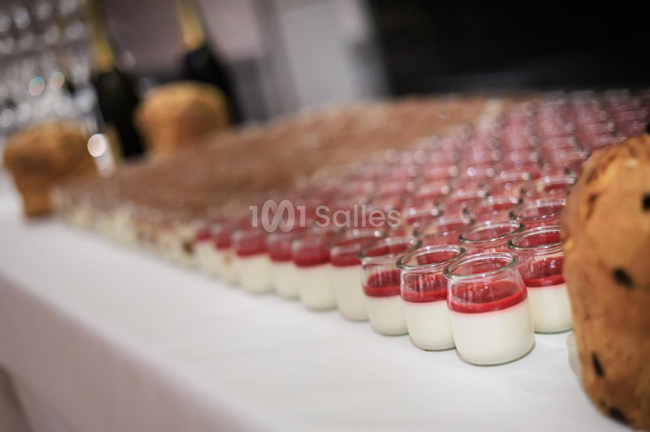 Alignement de verrines en verre avec couche de crème blanche et coulis rouge, accompagnées de petits gâteaux.