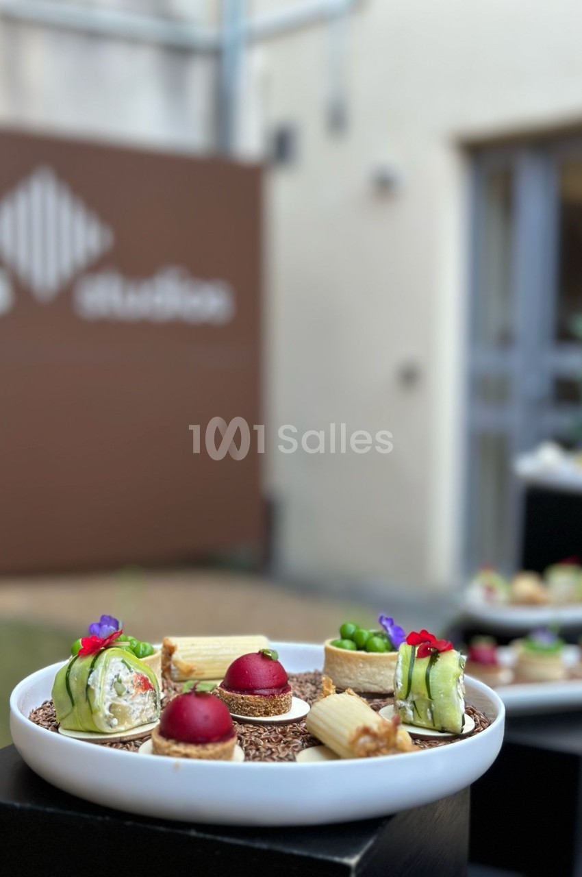 Assiette de dégustation avec amuse-bouches gastronomiques devant bâtiments de pierre.