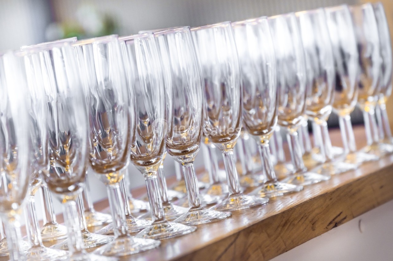 Range de flûtes à champagne vides alignées sur une table en bois, prêtes pour un événement.