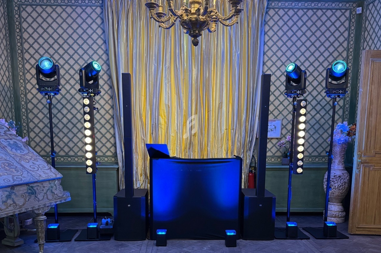 Installation de matériel de sonorisation et éclairage avec une console DJ dans une salle au décor classique.