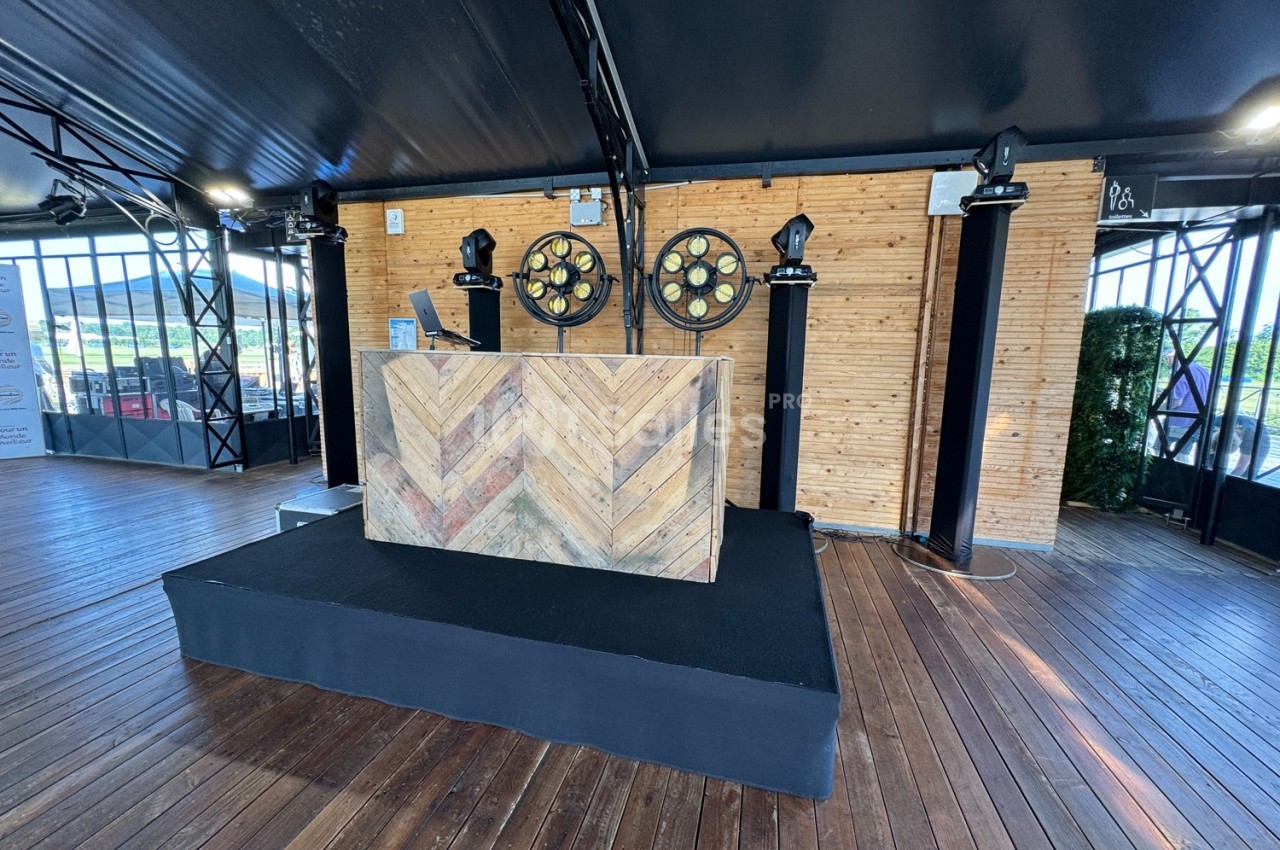 Scène en bois avec un pupitre décoré de motifs en chevrons, éclairée par des projecteurs circulaires.