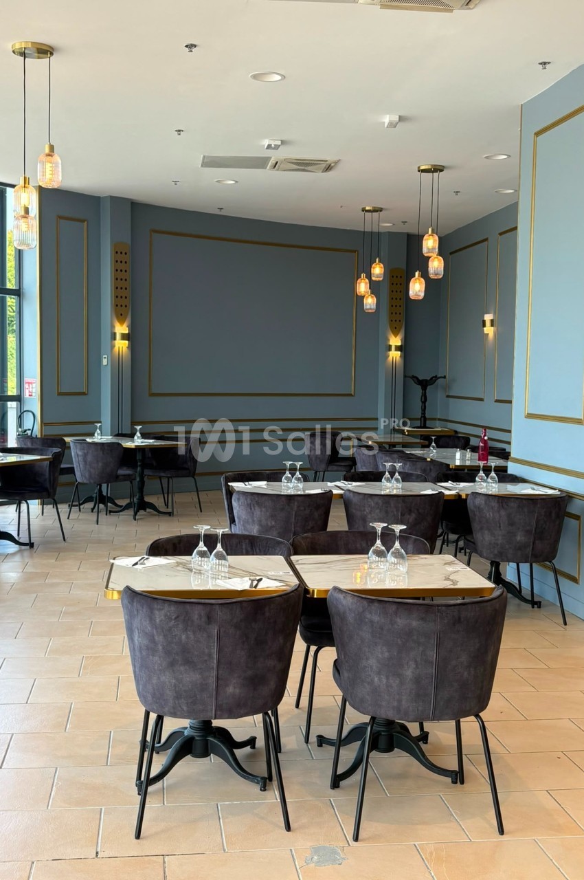 Salle de restaurant élégante avec tables en marbre, chaises en velours sombre et luminaires suspendus.