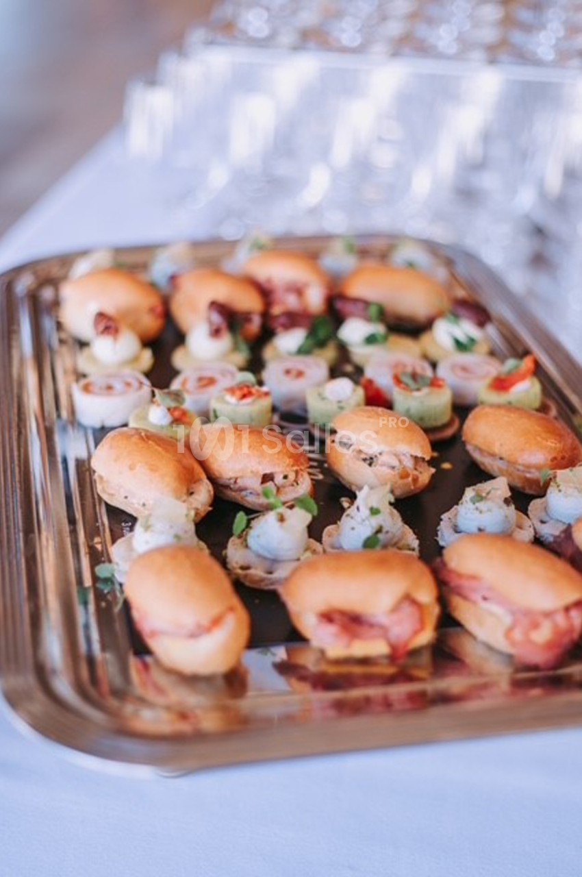 Plateau de petits fours variés comprenant des mini-sandwichs et des bouchées apéritives, disposé sur une table.