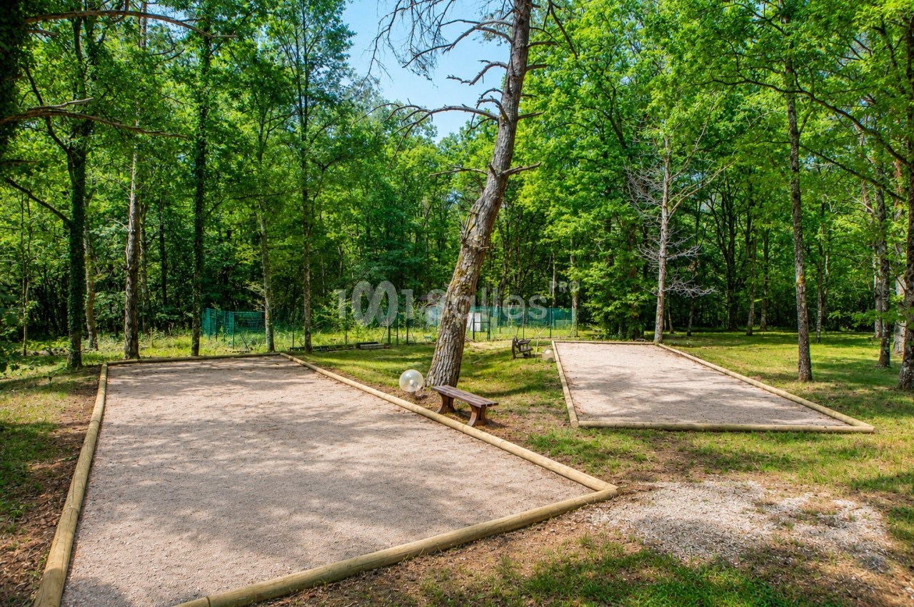 Terrains de pétanque en plein air entourés d'arbres dans un espace vert.