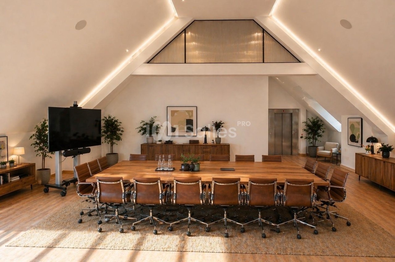 Salle de réunion spacieuse avec une grande table en bois, chaises en cuir, écran et décoration moderne.