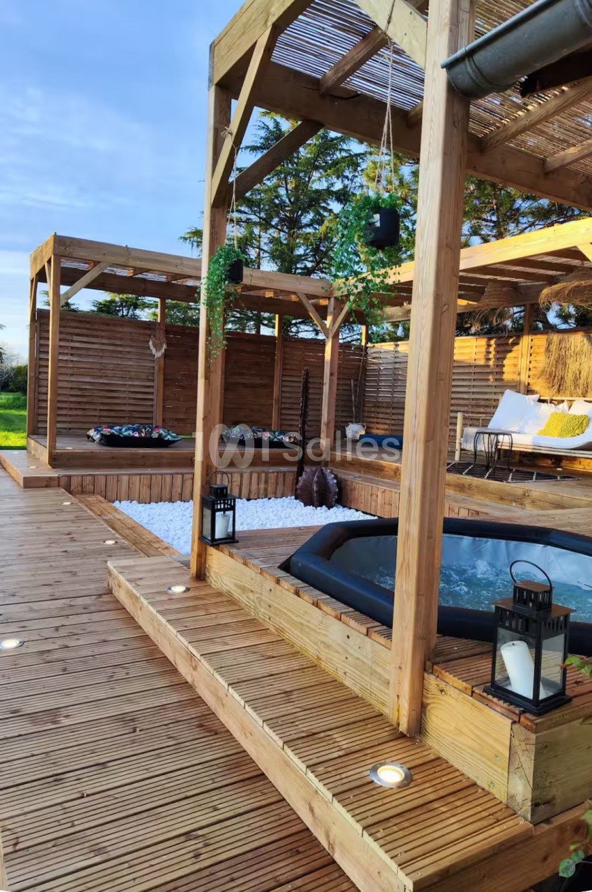 Terrasse en bois avec pergolas, spa et espaces de détente aménagés sous structure couverte.