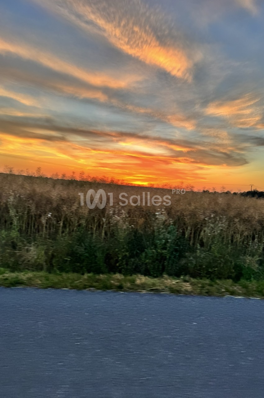 Coucher de soleil sur une rivière avec berges boisées en arrière-plan.
