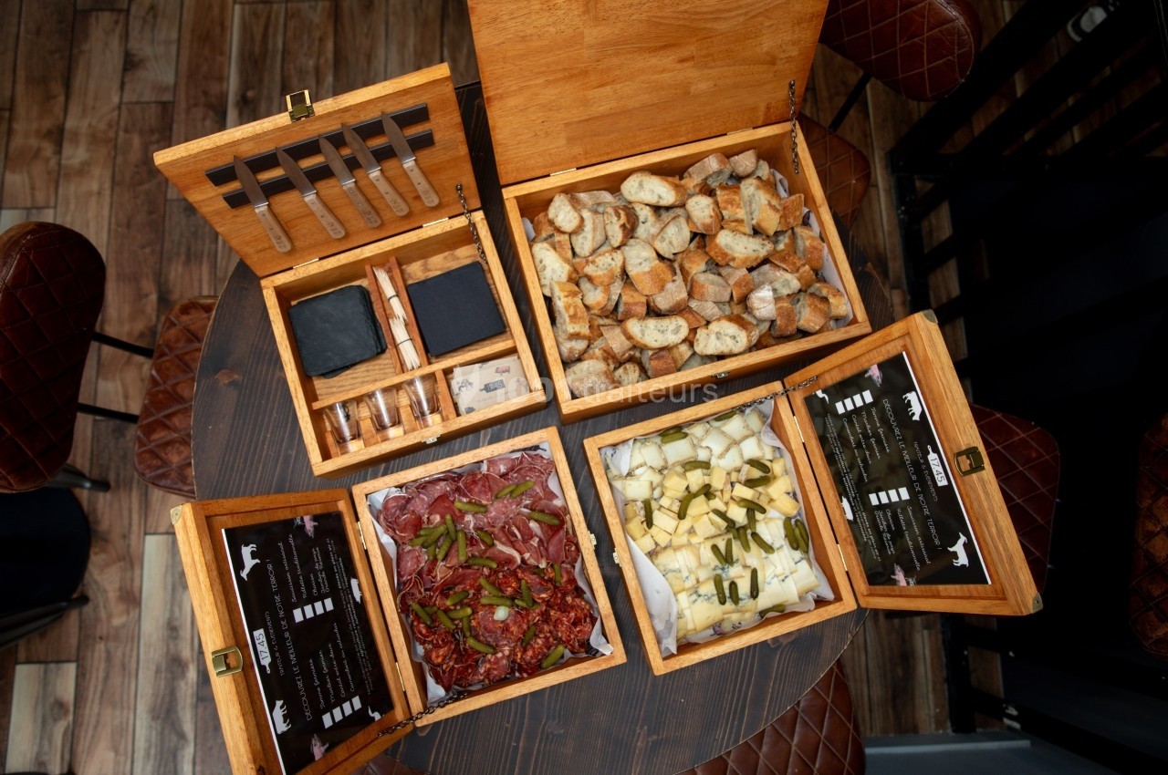 Coffret en bois ouvert contenant couteaux, pain grillé, charcuterie et fromage - vue de dessus.