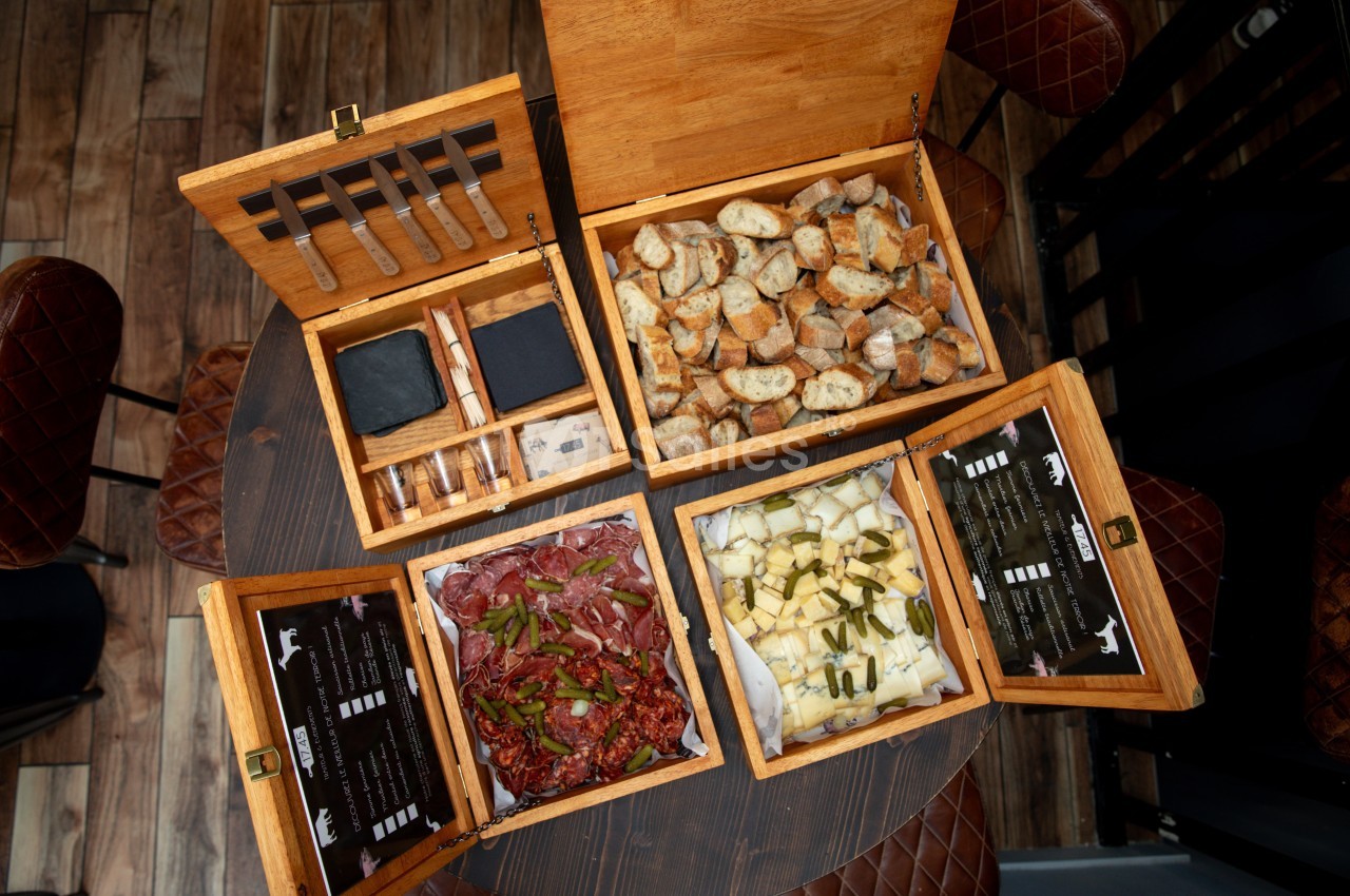 Coffret en bois ouvert contenant couteaux, pain grillé, charcuterie et fromage - vue de dessus.