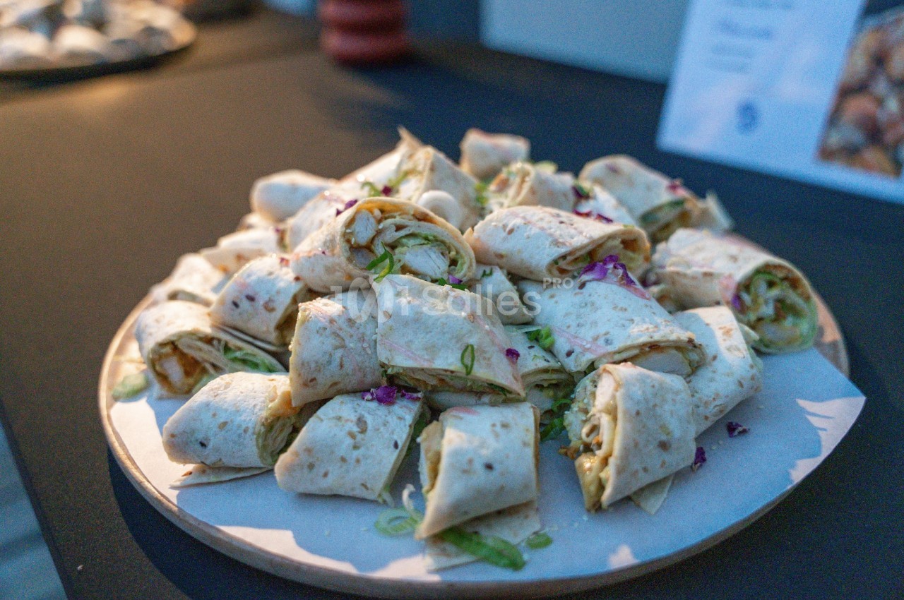 Assiette de wraps tranchés garnis de verdure et fleurs comestibles violettes.