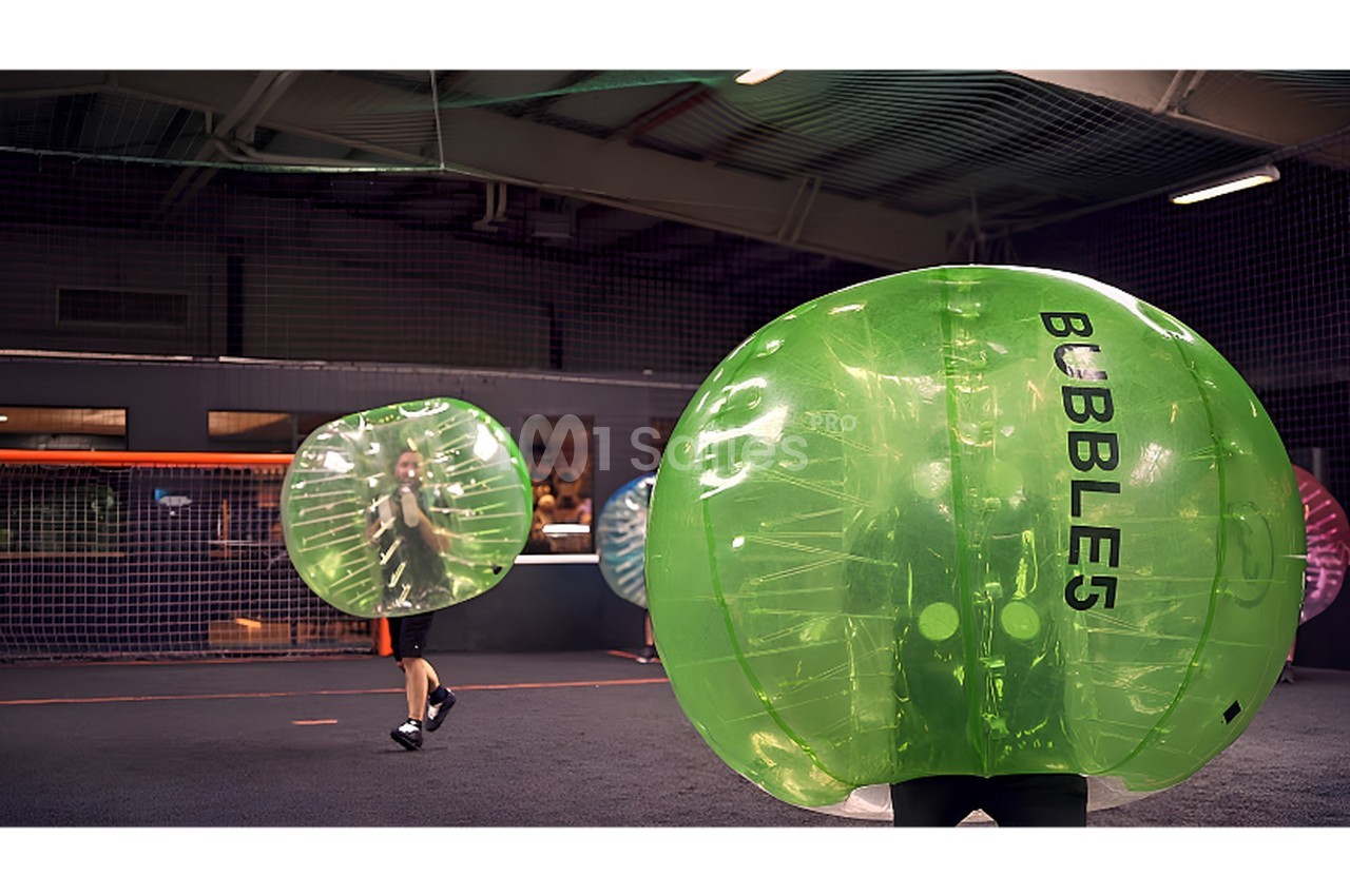 Intérieur d'espace d'activités avec bulles gonflables vertes transparentes pour jeu collectif.