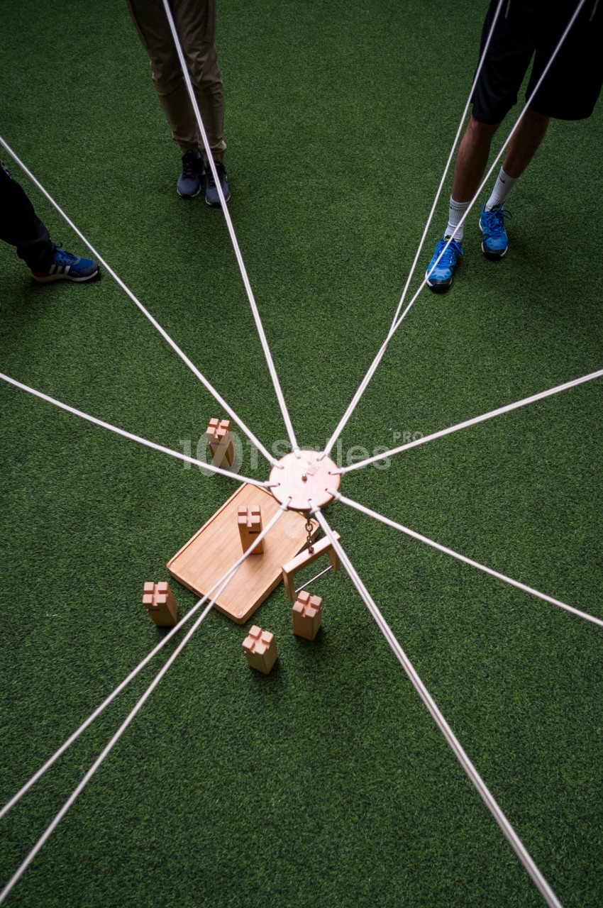 Vue zénithale de quatre joueurs autour d'un terrain de minigolf, bâtons et balles en jeu.