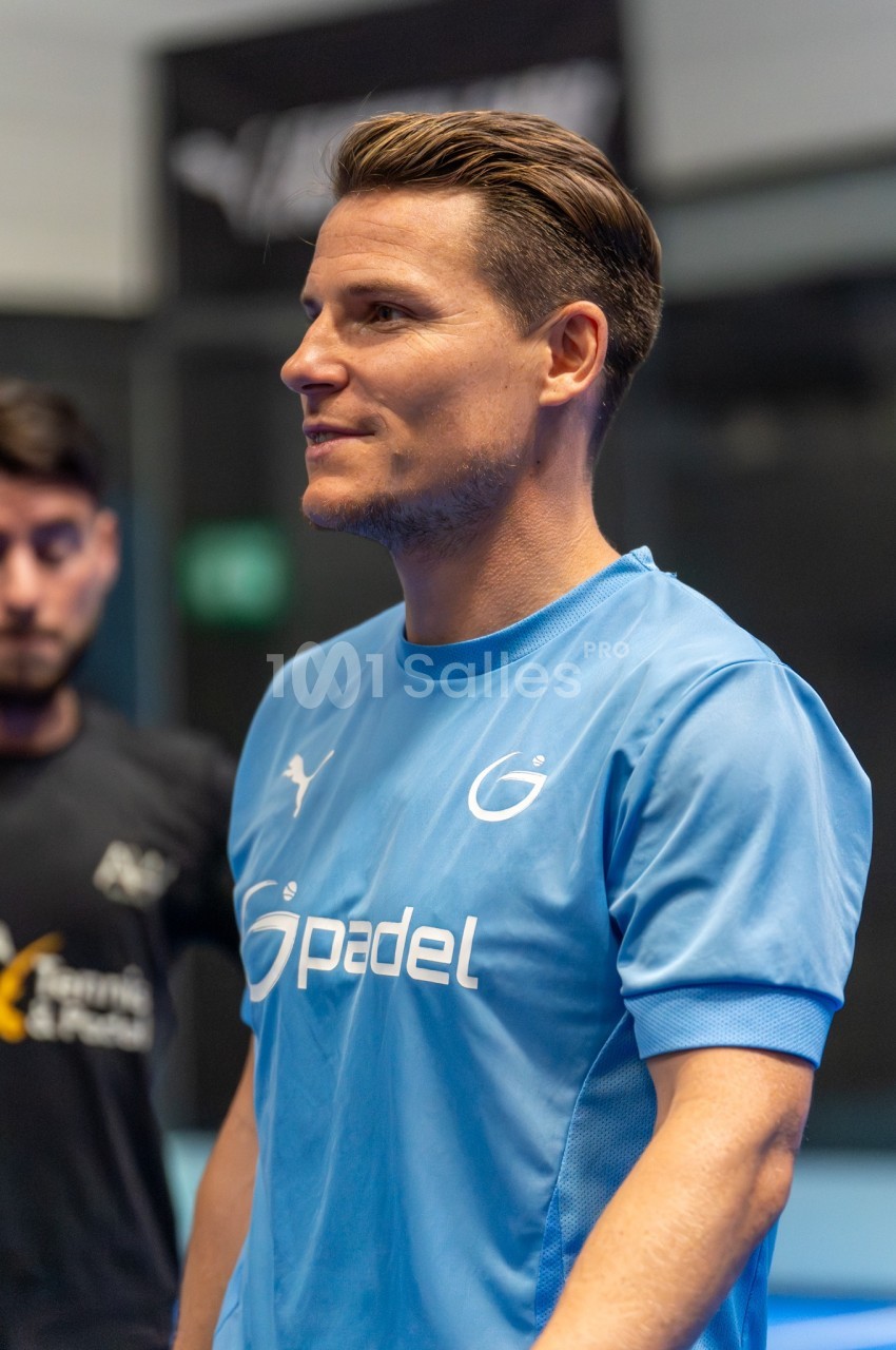 Homme en tenue de sport bleue lors d'une activité de padel en salle.