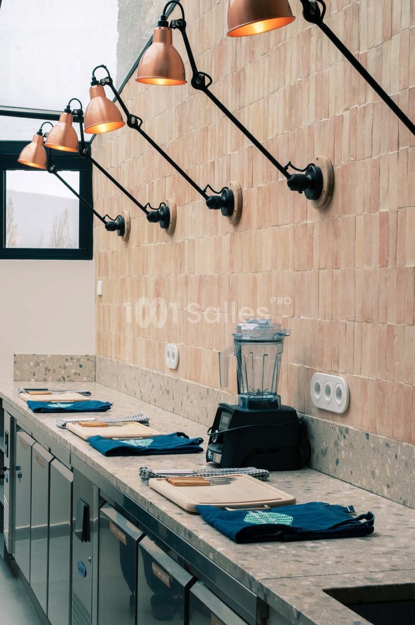 Cuisine équipée avec comptoir en pierre, luminaires industriels cuivrés et mur en brique terracotta - La Pensée Sauvage.