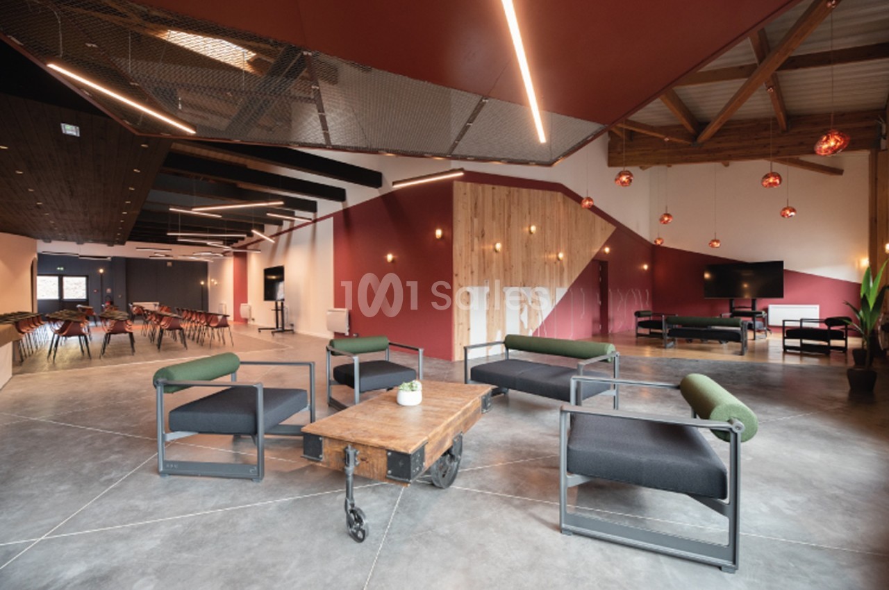 Espace intérieur moderne avec fauteuils, table basse en bois, éclairage suspendu et murs aux tons rouges et bois.