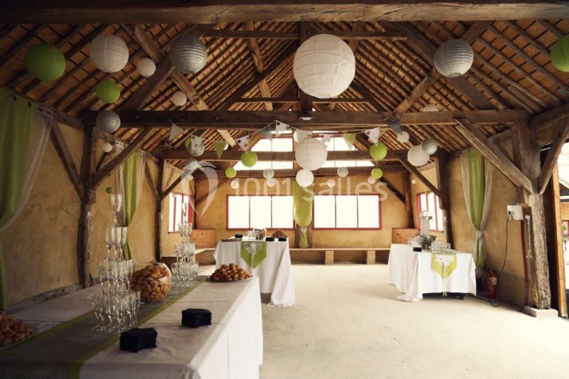 Salle de réception rustique décorée de lanternes suspendues, avec tables dressées pour un buffet.