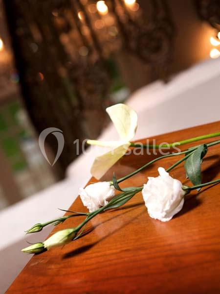Fleurs blanches posées sur une table en bois, avec un fond flou de lumières et de décorations.