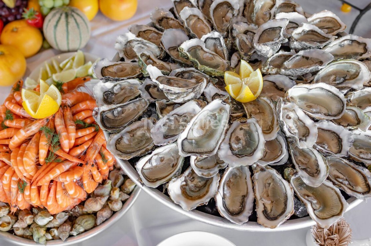 Plateaux de fruits de mer avec huîtres, crevettes, coquillages et citrons, disposés sur une table festive.