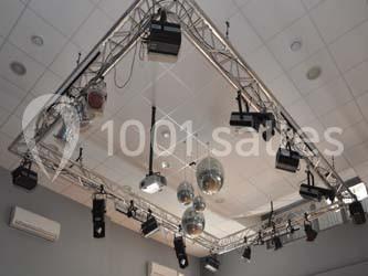 Structure métallique suspendue avec projecteurs, spots et boules à facettes dans une salle au plafond blanc.