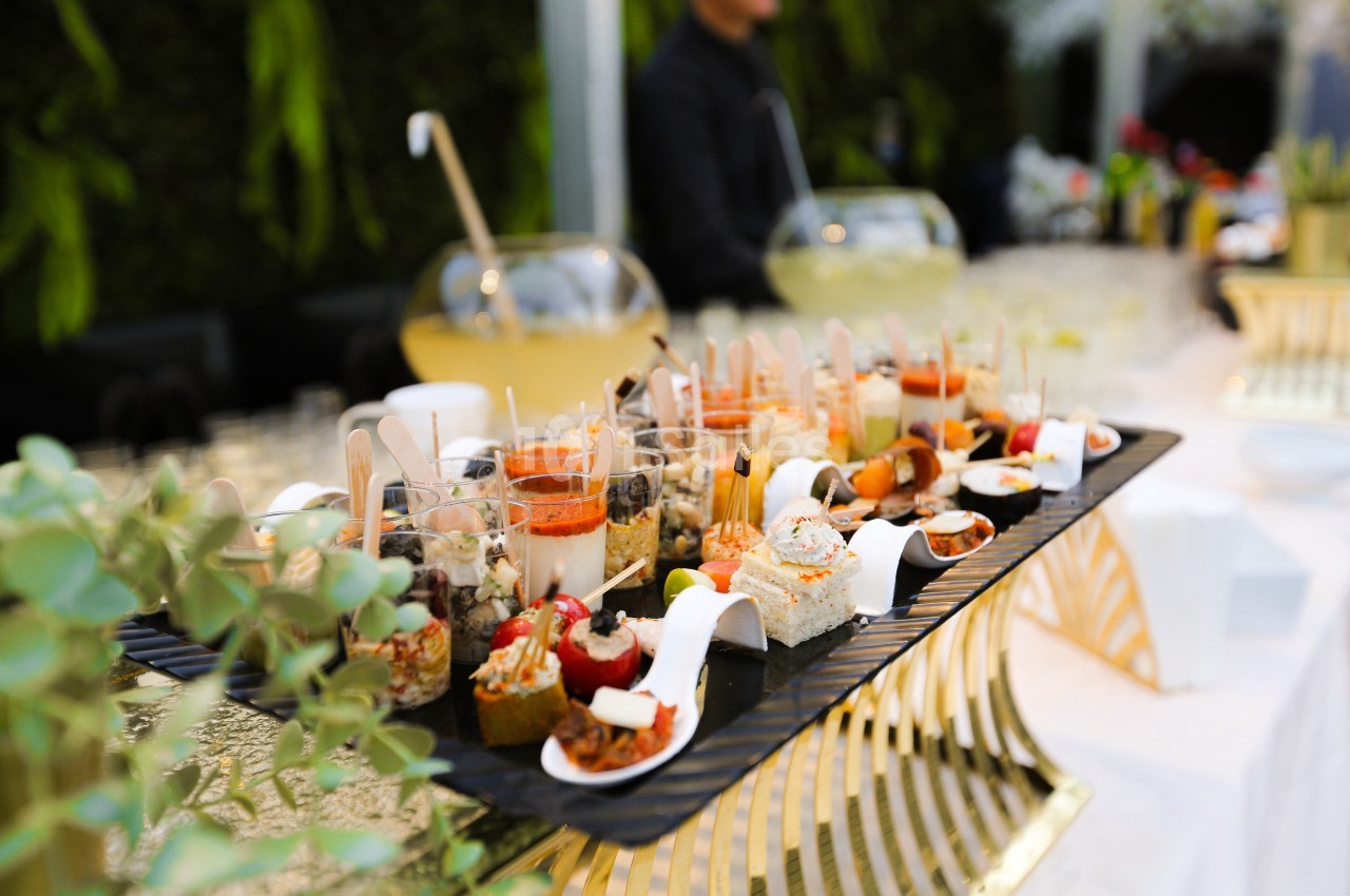 Plateau de verrines et amuse-bouches variés disposés sur une table lors d'un événement en extérieur.