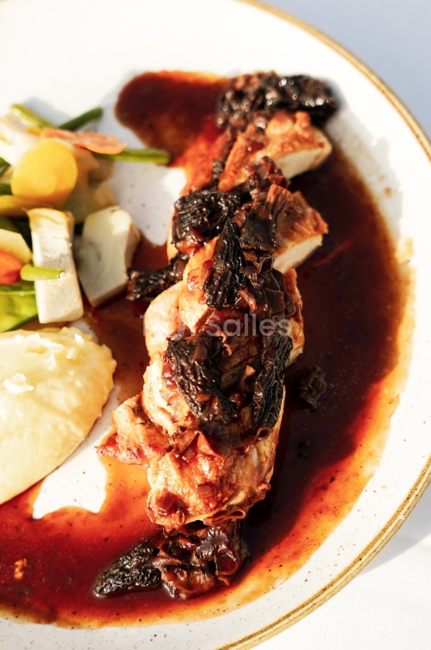 Plat de volaille nappée de sauce brune, accompagnée de purée et légumes colorés sur une assiette blanche.
