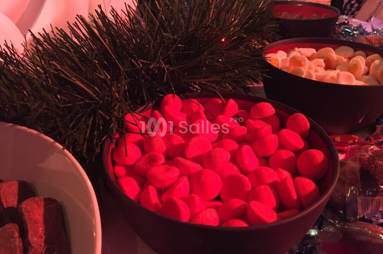 Bol de bonbons rouges entouré de décorations de Noël et d'autres bols de friandises.