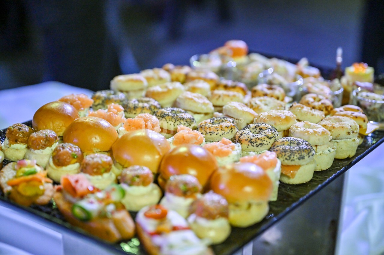 Plateau de petits pains et amuse-bouches variés garnis de saumon, fromage et autres ingrédients, présenté sur une table.