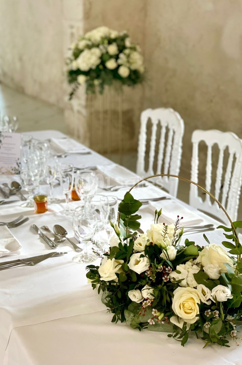 Table de réception élégamment dressée avec une décoration florale composée de roses blanches et de feuillages.